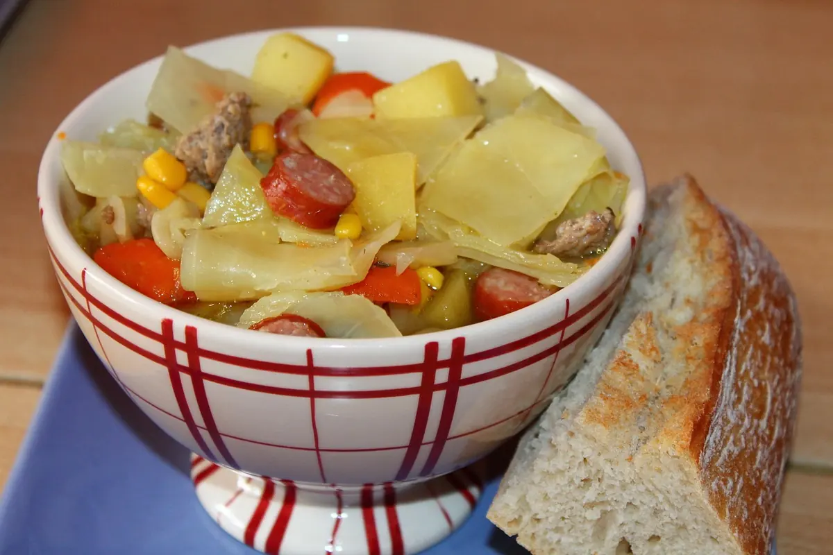 Bowl of vegetable and sausage stew with a slice of bread